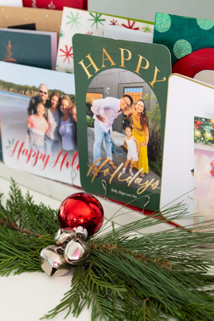 Completed Christmas card holder with greenery in front of it on a console table.