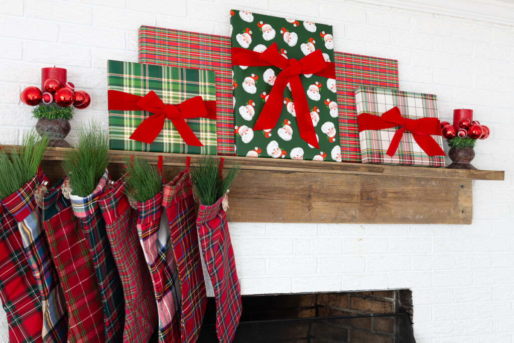 Red, green and white Christmas decorated fireplace mantel using holiday gift wrap and ribbon.