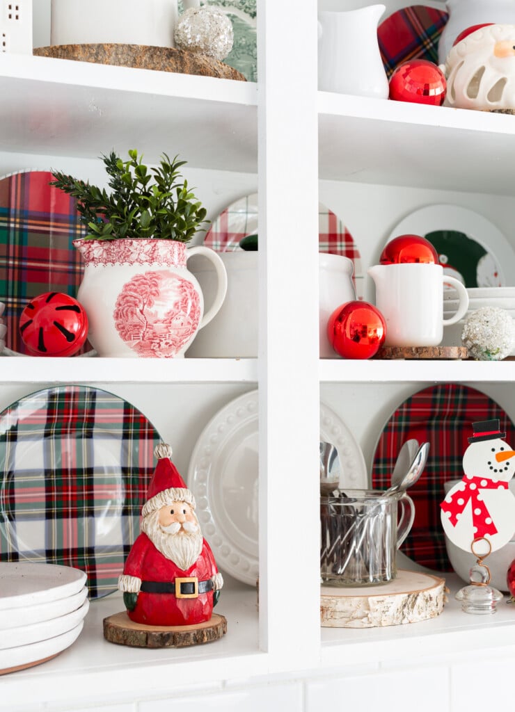 decorating shelves for Christmas in a kitchen using traditional holiday colors.