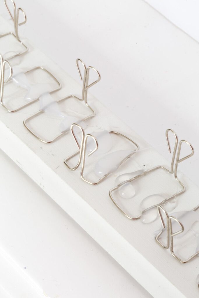 close up of owl style paper clips attached to scrap wood to make a holiday card holder.