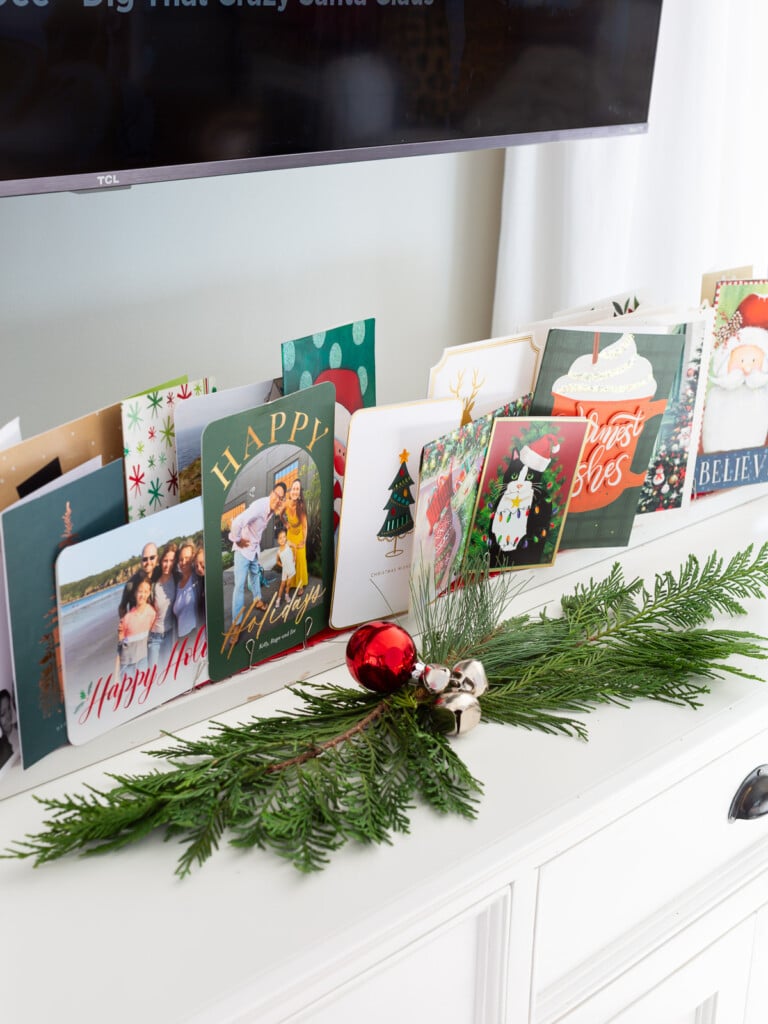 long display of Christmas cards on a console table.