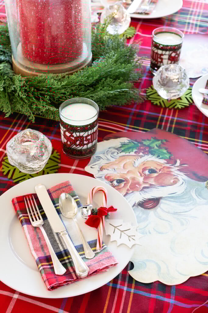 Christmas round table set up with a red plaid tablecloth and Santa Claus face paper placemats.