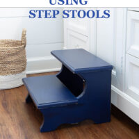 Navy blue painted wood step stool placed in front of a white sink vanity in a bathroom. Text overlay says - Decorating Ideas Usind Step Stools