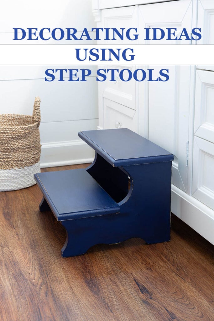 Navy blue painted wood step stool placed in front of a white sink vanity in a bathroom. Text overlay says - Decorating Ideas Usind Step Stools