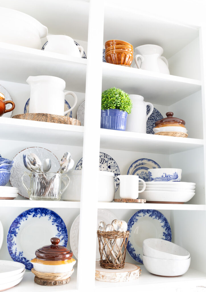 Open white shelves in kitchen decorated with blue, white and brown items.