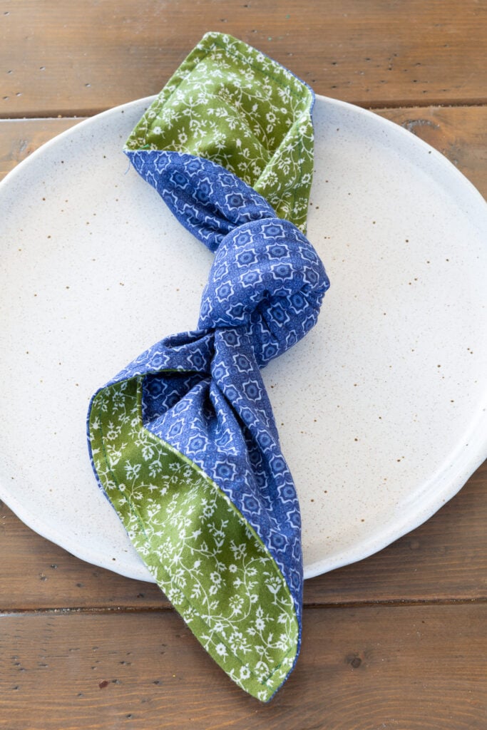 blue and green patterned napkin knotted on a dinner plate