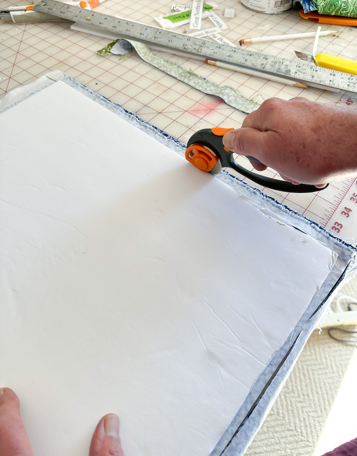 Cutting out 2 pieces of fabric using a foam board template and a rotary cutter.