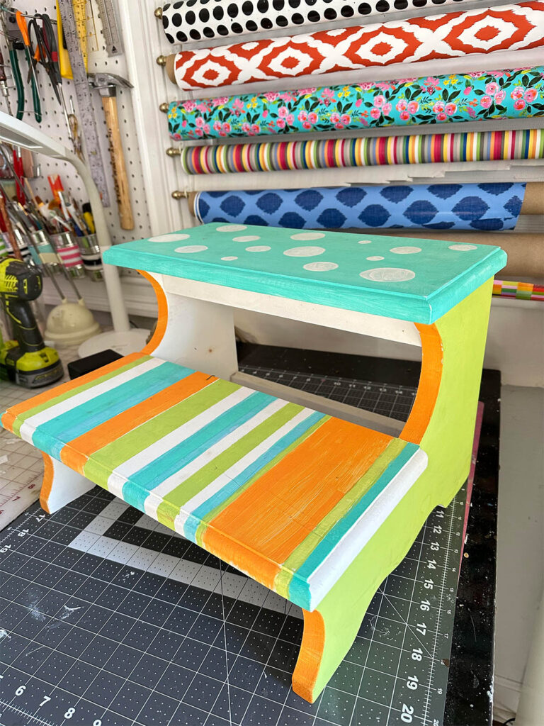 Thrift store find wood step stool painted in neon colors, stripes and dots waiting for a makeover.