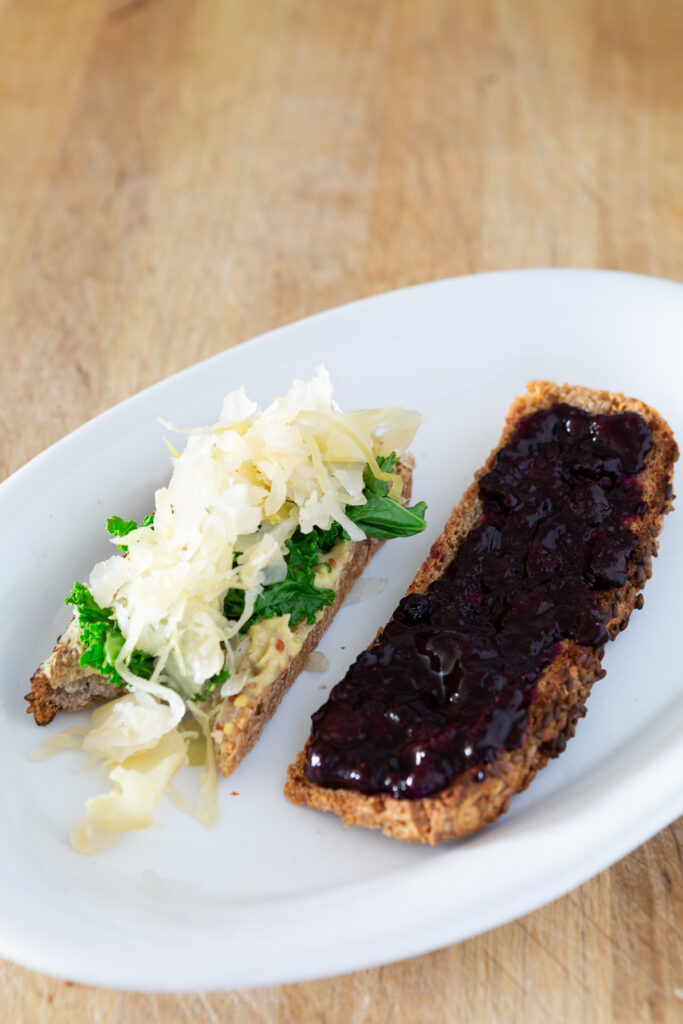 2 slices of buckwheat toast. One with a savory topping and the other a sweet spread.