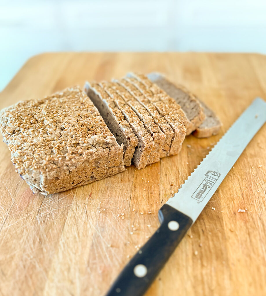 sliced buckwheat bread on a cutting board with a bread knife.