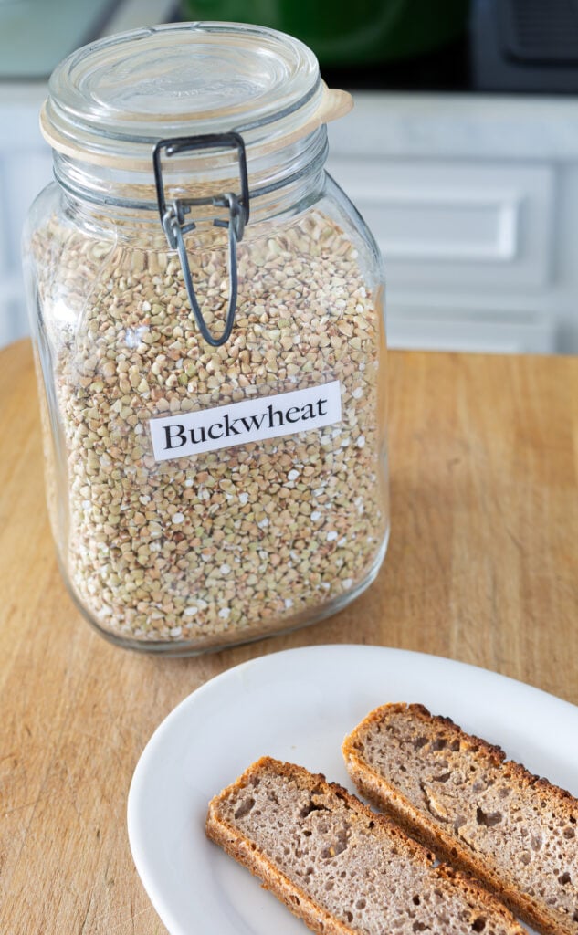A glass jar filled with buckwheat groats and two slices of buckwheat bread on a plate