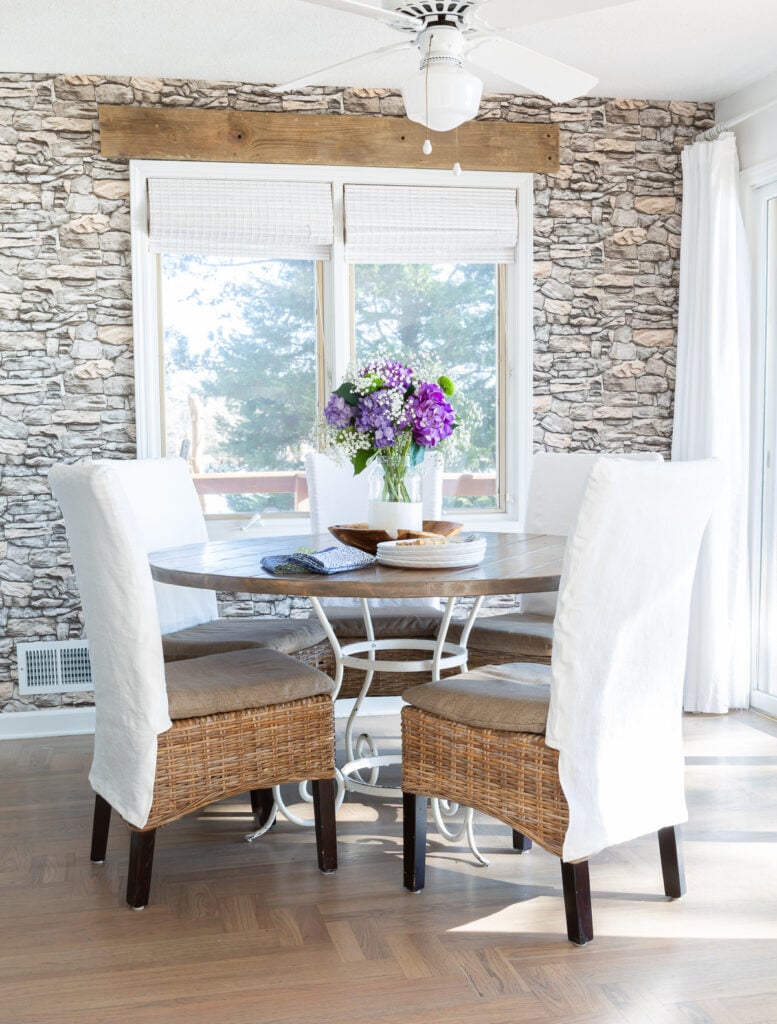 Kitchen table with 5 dining chairs around it each with a white slipcover.