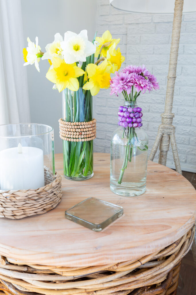 1 glass vase and 1 glass bottle with old jewelry necklaces wrapped around them to create colorful spring decor.