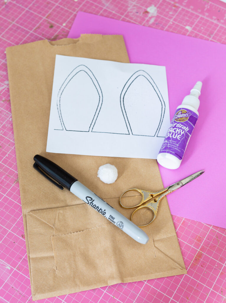 supplies and bunny ear template needed to make an Easter bunny bag using a brown paper bag.