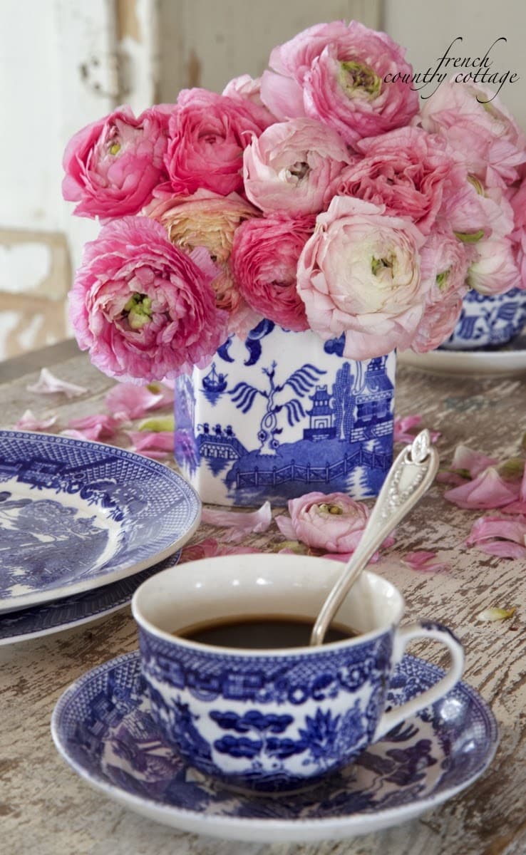 Roses in a blue and white vase and a coffee cup on a table from French Country Cottage