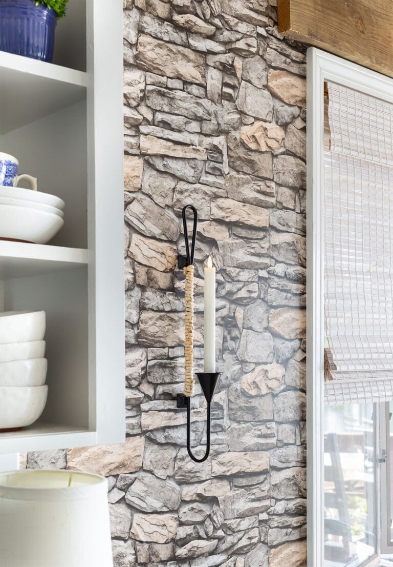 Black metal and natural cord wrapped candle sconce hanging on wall in kitchen.