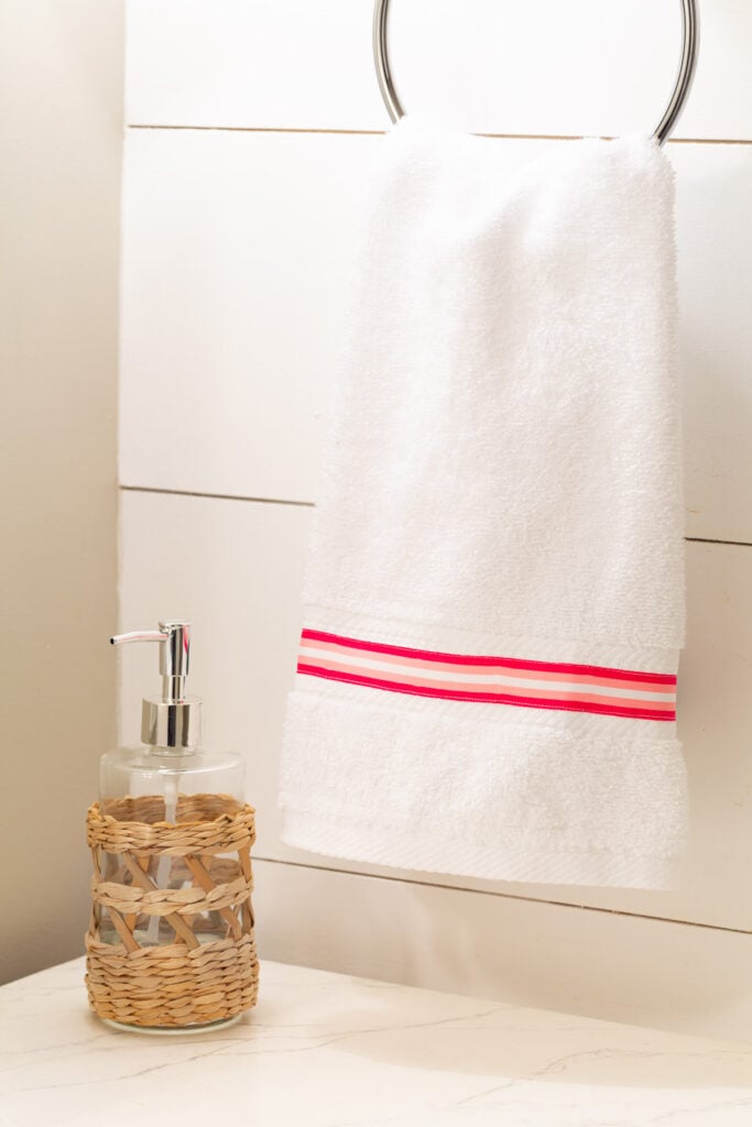 pink and white stripe ribbon sewn onto a bathroom hand towel.