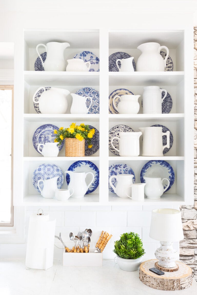 Blue and white decor accents on open shelves in a white kitchen.