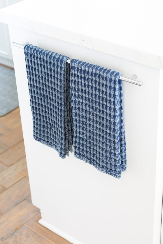 blue waffle weave dish towels hanging on a towel rack in a kitchen.