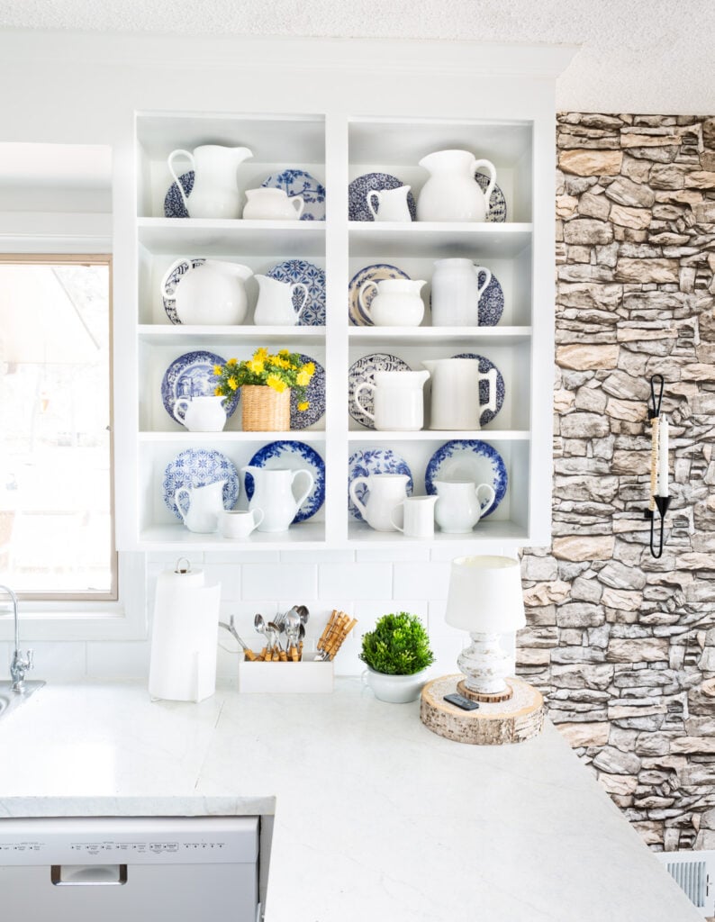 Neutral white kitchen with stone wall and white and blue accent decor.