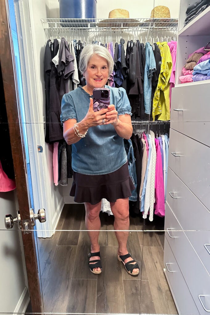 Blogger, Diane Henkler standing in her clothes closet after cleaning and organizing it top to bottom.