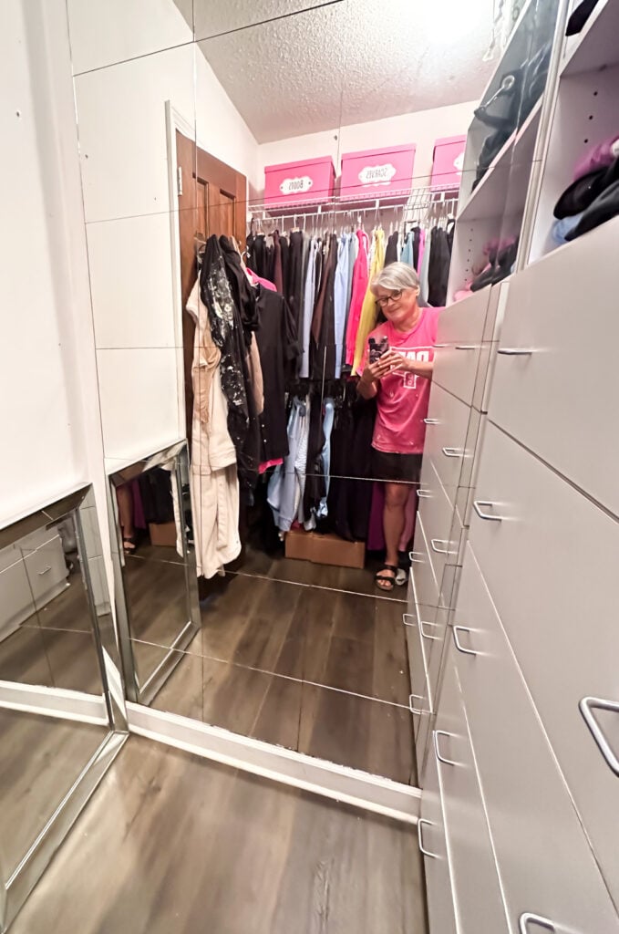 Walk in clothes closet with wire shelving, tile mirrors and built in drawers.