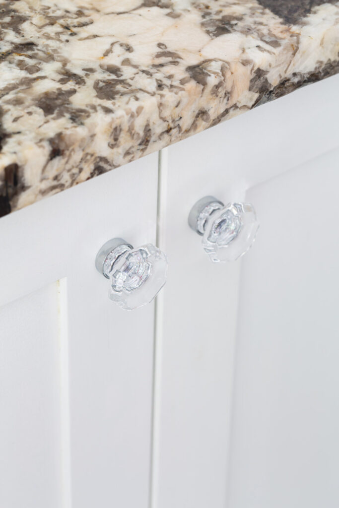 glass and polished chrome cabinet knobs on white bathroom cabinets.