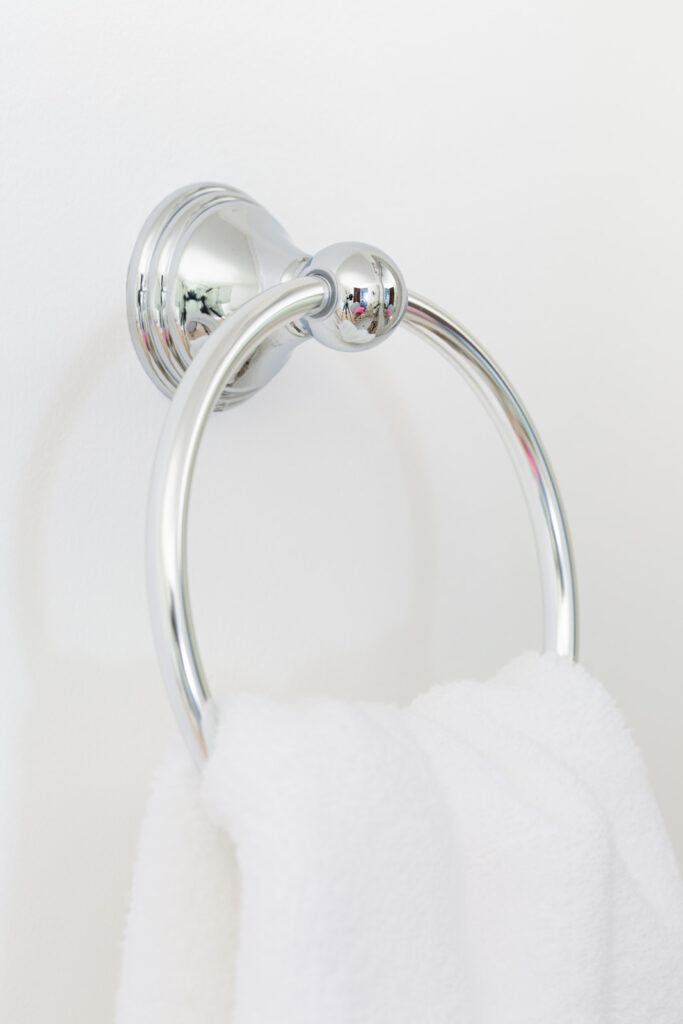 polished chrome towel ring on white wall.