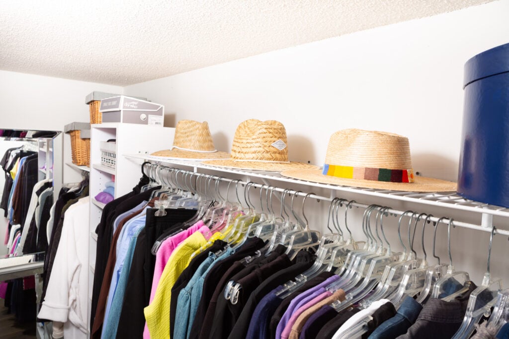 3 hats and a hatbox on top of a closet shelf.