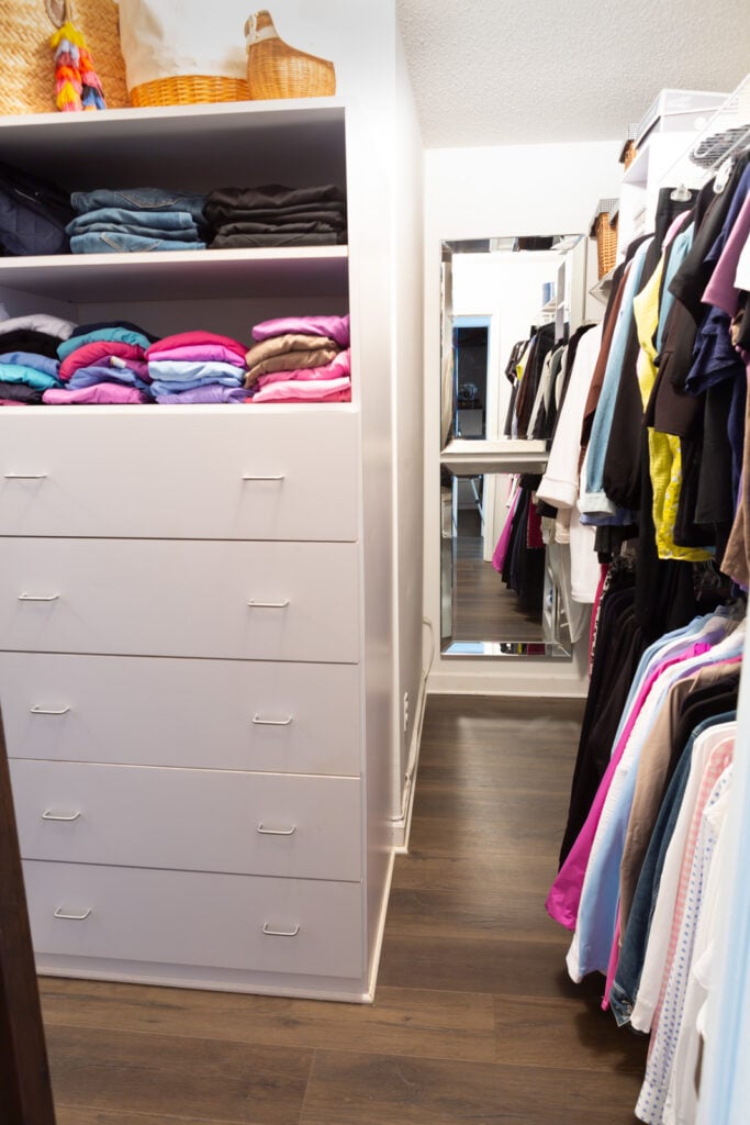Full look into a walk in closet after cleaning it out and reorganizing the clothes and items in it.