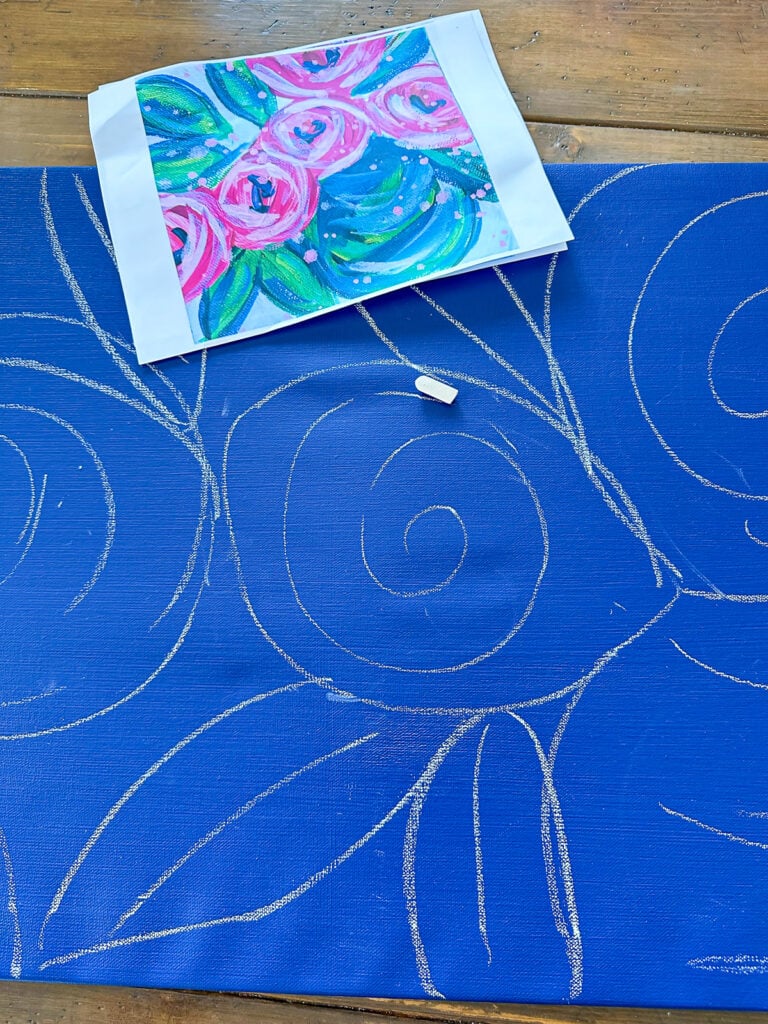 sketching blue painted art canvas with white chalk to draw flowers and leaves