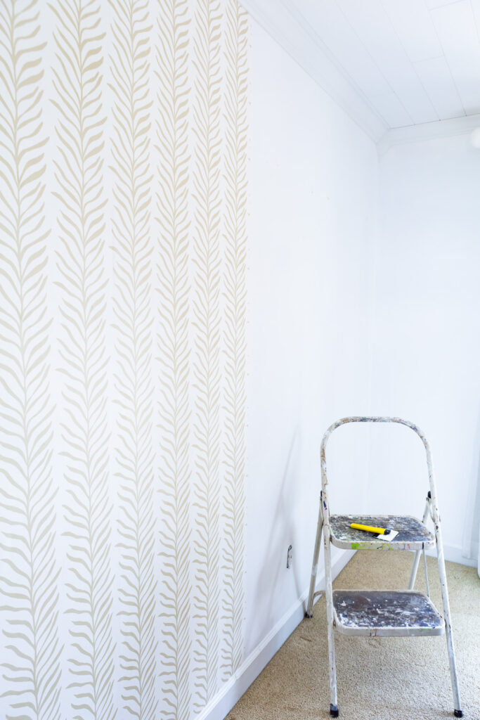 Installing panels of Love Vs Design wallpaper on a wall.