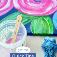 pink flowers painted on a blue art canvas - text says get the quick tips painting an artist canvas.