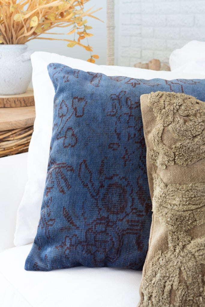 Two Fall colored throw pillows lined up on a white sofa.