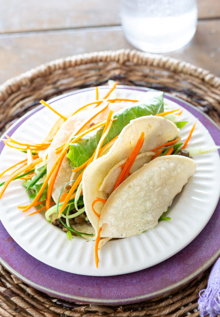 white ridged dessert plate from McGee & Co on top of a purple plate from a thrift store. Filled with veggie tacos.