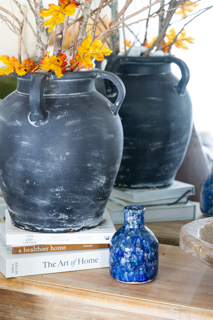 close up of a small blue crackle painted vase on a wood console table.
