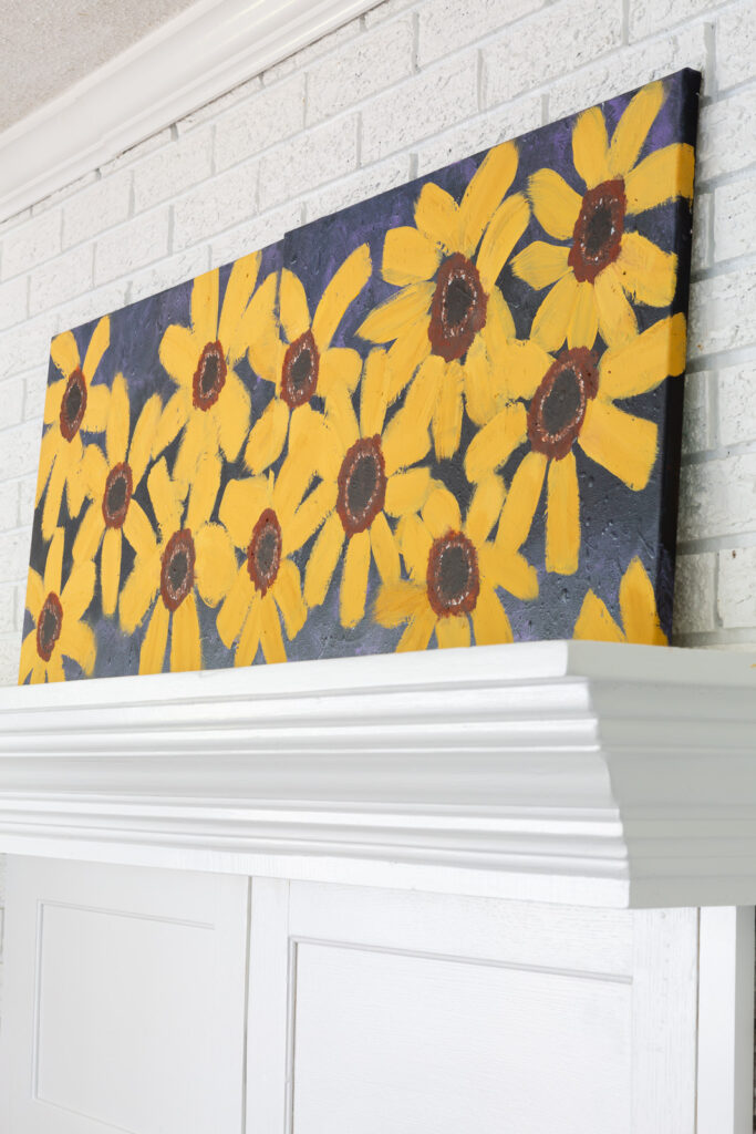 Close up of fall flowers painted on two large canvases that are placed side by side on a mantel.