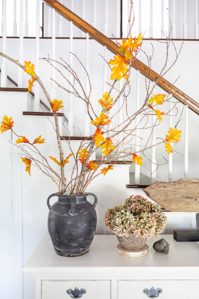 Single faux fall leaves added to real tree branches to decorate a home for fall.