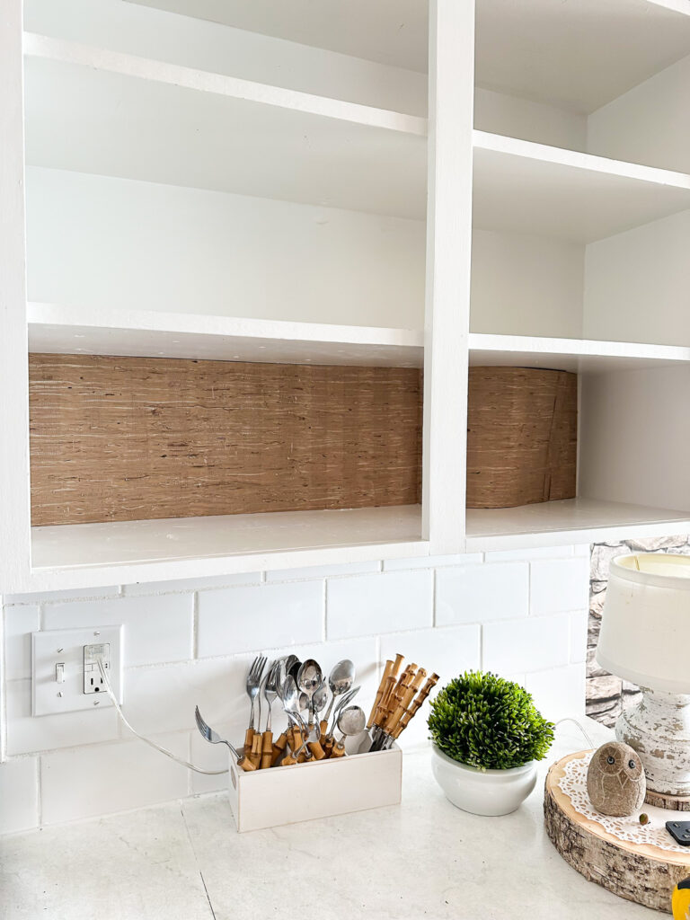 Add wallpaper to the back wall of open kitchen shelving to decorate it for autumn.