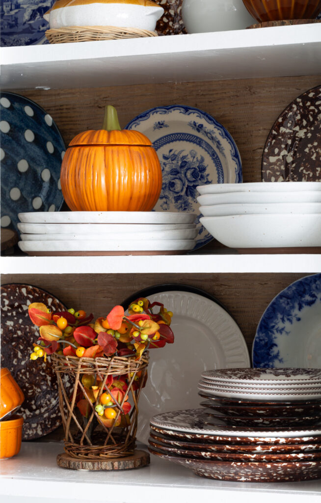Fall colored kitchen items displayed on open shelves in a small kitchen decorated for fall.