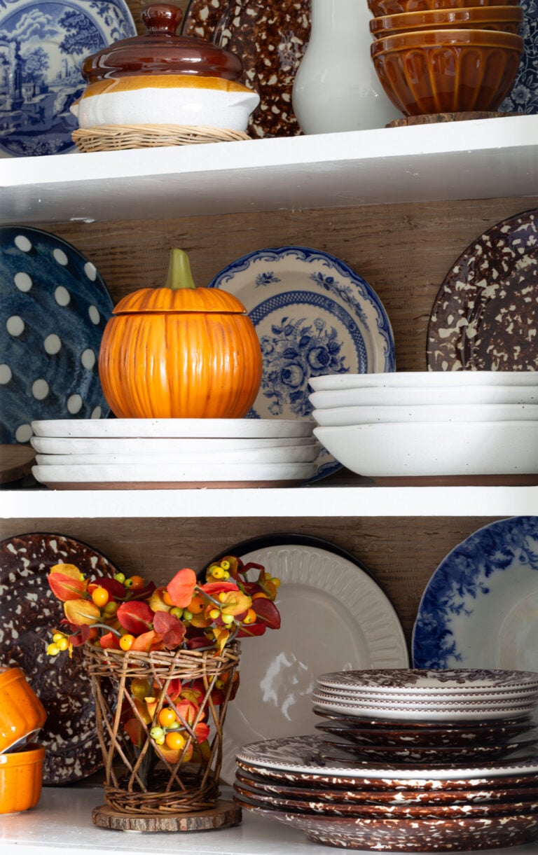 Fall colored kitchen items displayed on open shelves in a small kitchen decorated for fall.