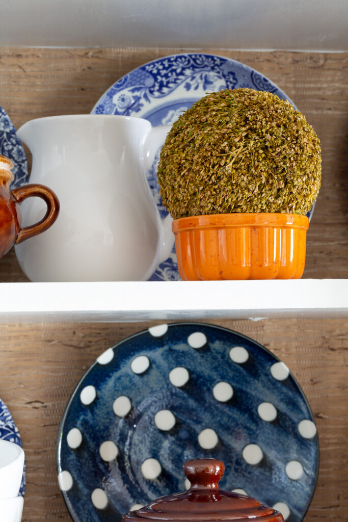 Fall colored kitchen items displayed on open shelves in a small kitchen decorated for fall.