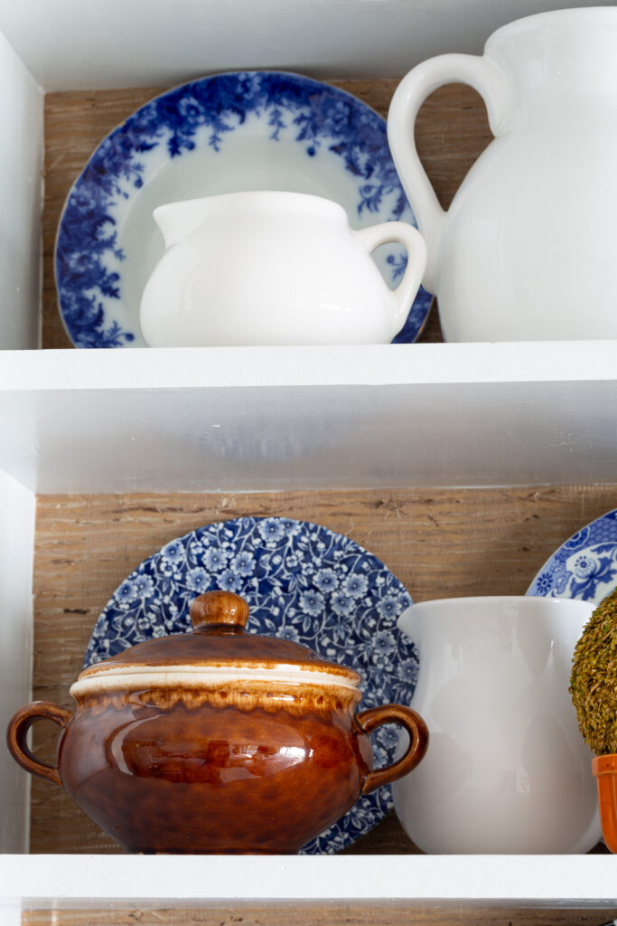 Fall colored kitchen items displayed on open shelves in a small kitchen decorated for fall.