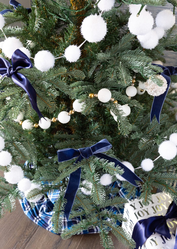 White snowball garland and blue bows on Christmas tree.