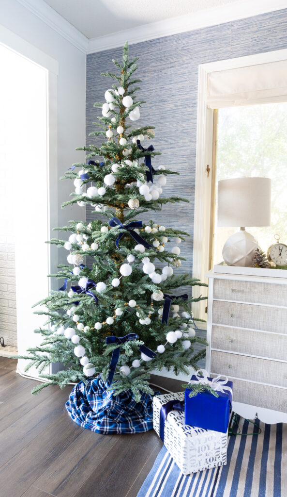 7' King Noble Fir Artificial Christmas Tree with 500 Warm White LED Lights decorated with white snowball garland and blue ribbon bows.