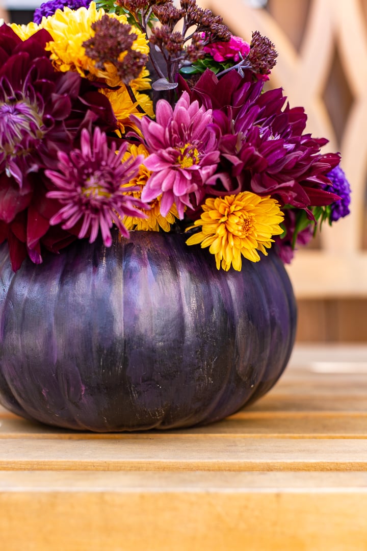 pretty pumpkin painted a deep shade of purple with colorful mums inside.