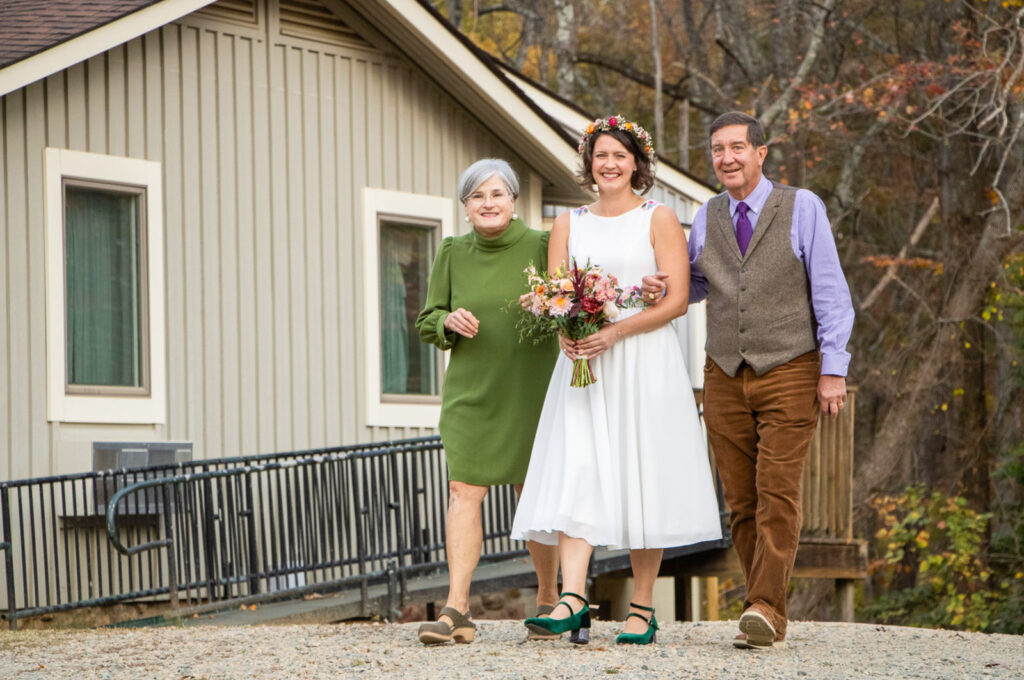 mom and dad walking bride to outdoor wedding.