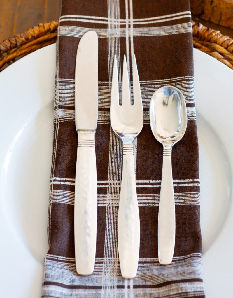 a place setting of Swedish Modern Sterling by Allan Adler on a brown and white table