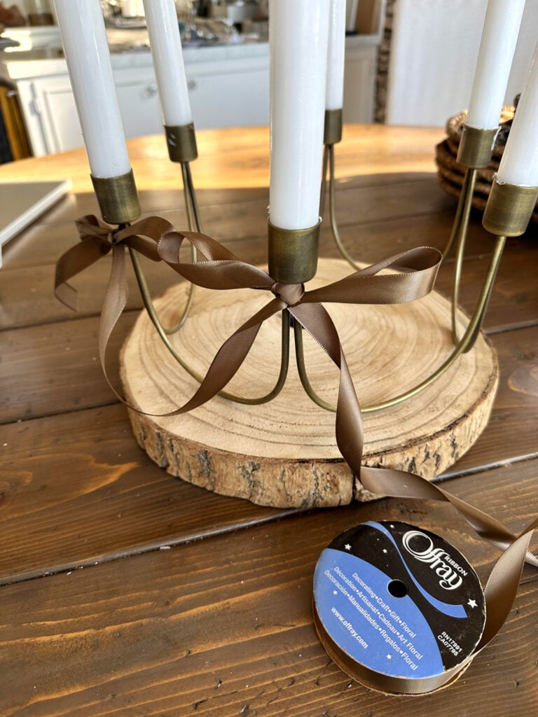 antique-brass-6-candle-centerpiece getting ribbon bows added to it.