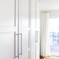View of two side-by-side IKEA PAX storage units in white in a multi-purpose room in a home.